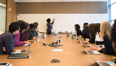 A work team watches a presenter while sitting at a conference table.