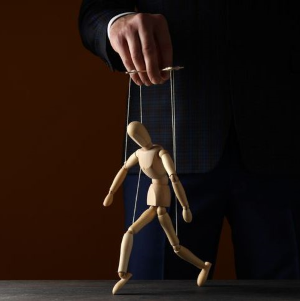 wooden figure with strings being held up by hand