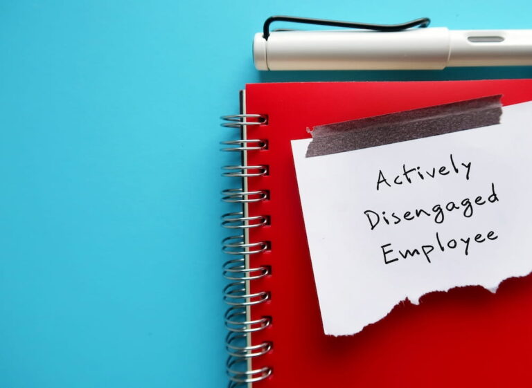 On blue copy space background, pen and torn paper on red norbook with handwritten text Actively Disengaged Employee - refers to unhappy employees who busy undermining workplace by getting others to share in their discontent