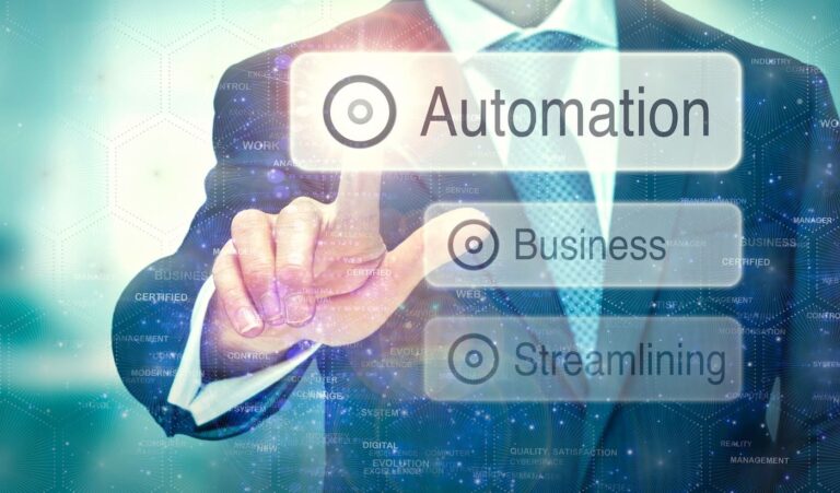 A businessman in a suit is touching a virtual screen, selecting the word “Automation” from a digital interface. Below it are the words “Business” and “Streamlining.” The background features abstract digital elements, hexagonal patterns, and tech-related words, symbolizing technology integration in modern business processes.