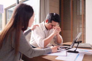 Compassionate woman comforts a stressed male colleague at the office desk providing emotional support during difficult business challenges or setbacks