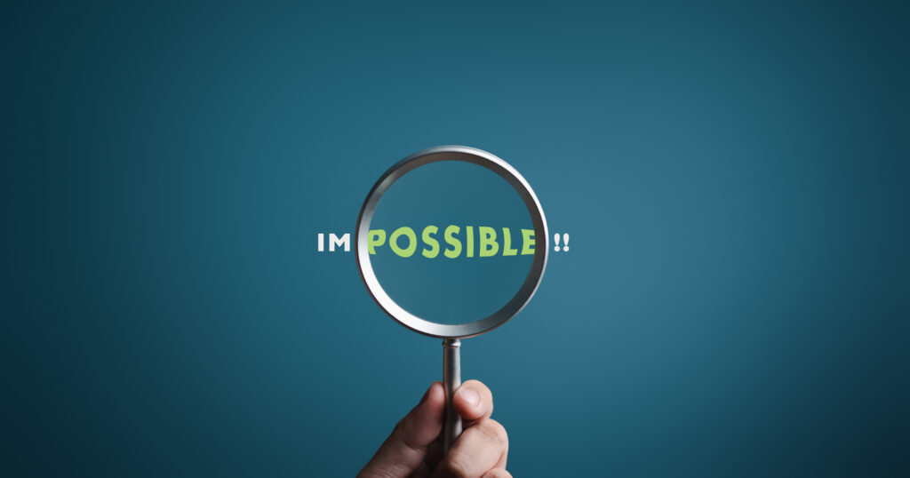 Magnifier focuses on word POSSIBLE side of the word IMPOSSIBLE. It is possible to motivational inspirational concepts. Unveiling the motivation concept. Blue background, flat lay.